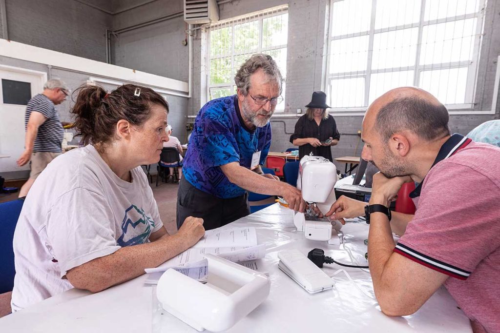 Two men repairing a woman's sewing machine