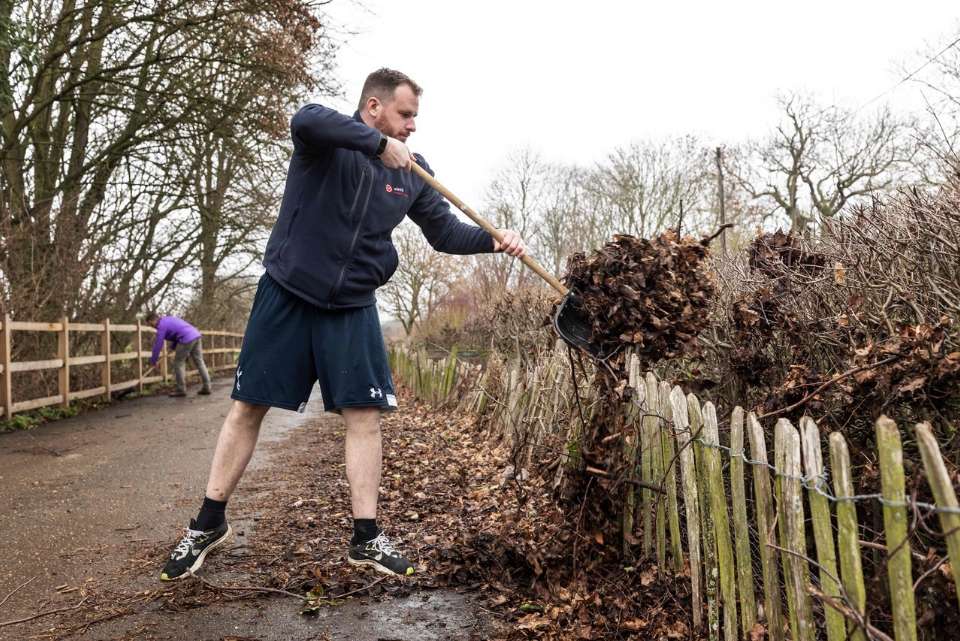 Volunteer shovelling leaves at Denny Abbey Farmland Museum