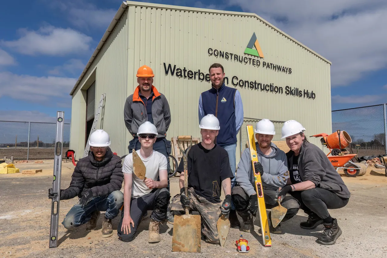 Constructed Pathways Students stood in front of a warehouse with hardhats and tools.